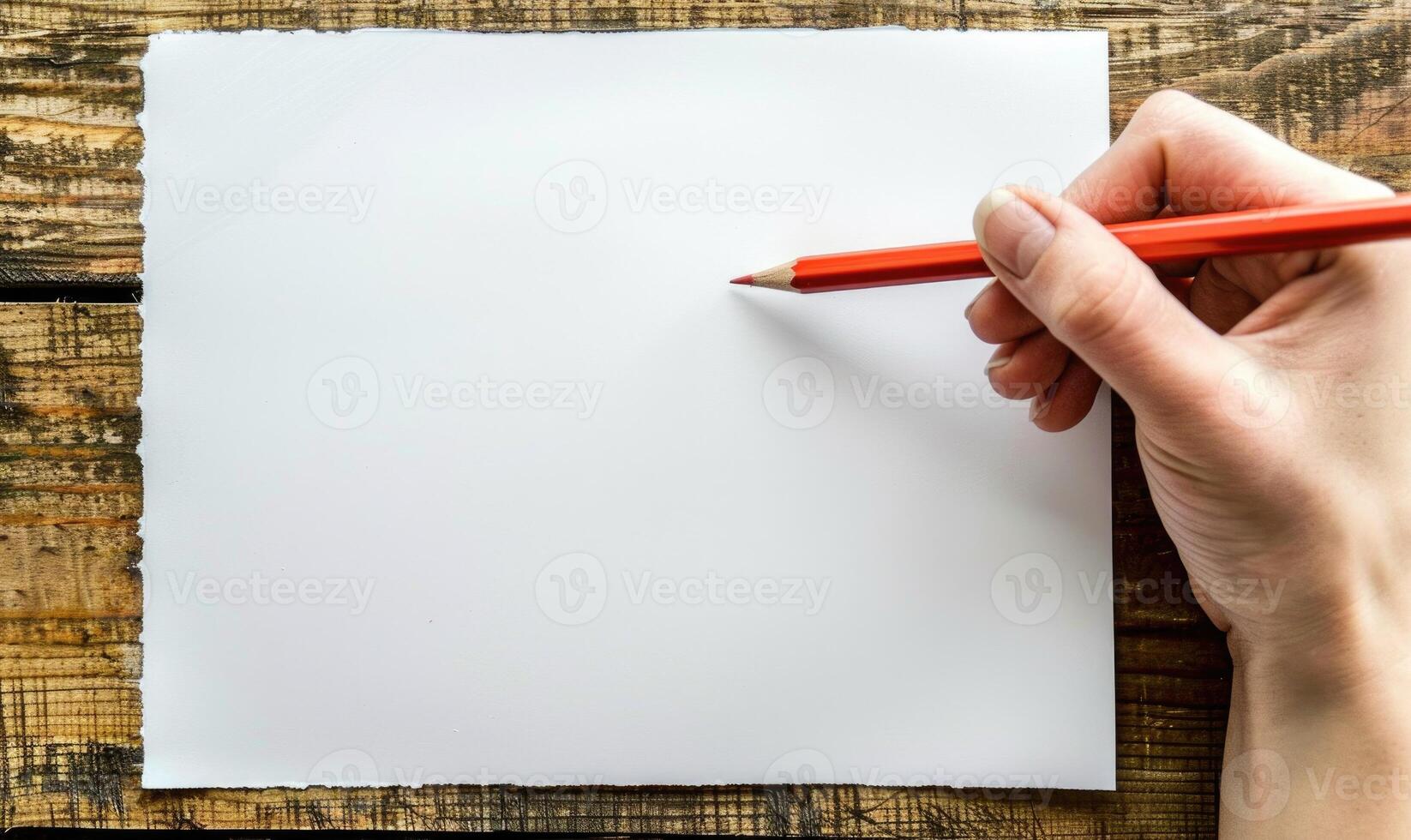 A hand holding a graphite pencil poised over a blank sheet of white paper photo