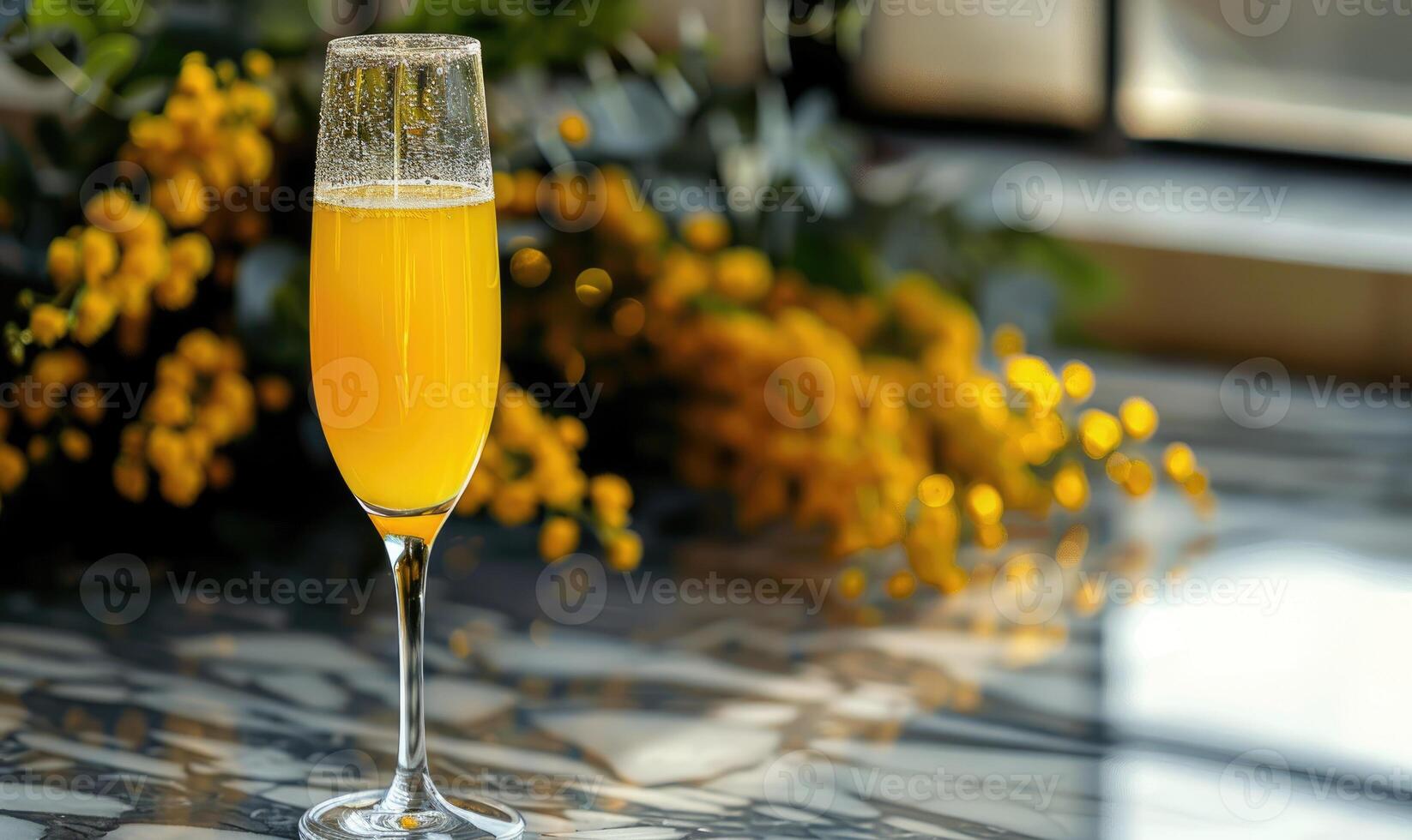 Cocktail in a glass goblet with mimosa branches in the background photo