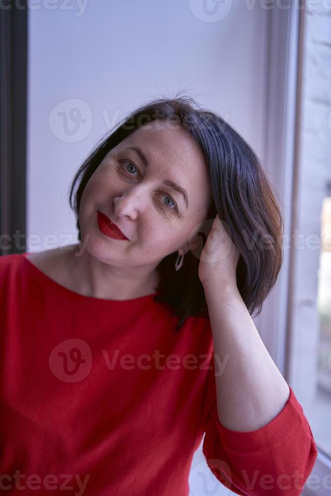 portrait of a brunette with a bob haircut in a red sweater and a leather mini skirt in the office photo