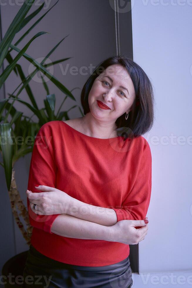 portrait of a brunette with a bob haircut in a red sweater and a leather mini skirt in the office photo