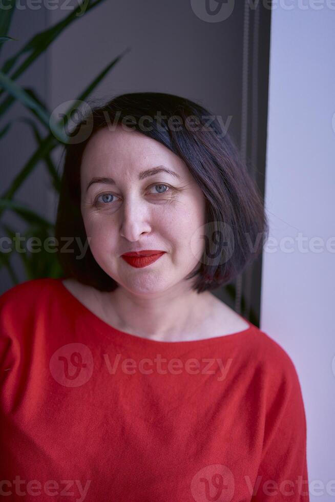 portrait of a brunette with a bob haircut in a red sweater and a leather mini skirt in the office photo