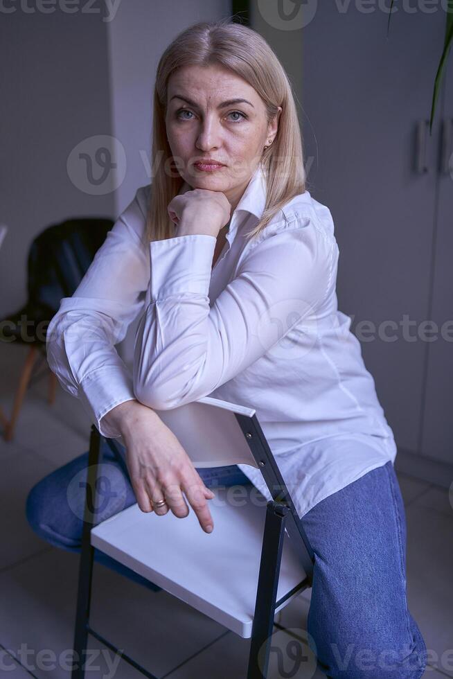 retrato de un rubia mujer en pantalones y un blanco camisa en el oficina foto