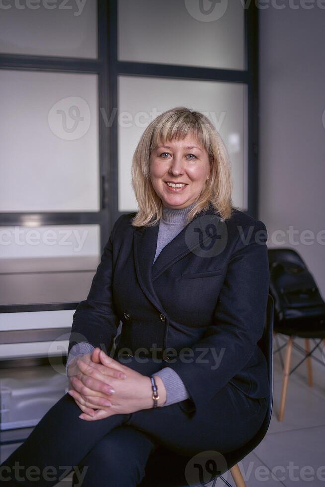 portrait of a blonde middle age woman in a business suit in the office photo