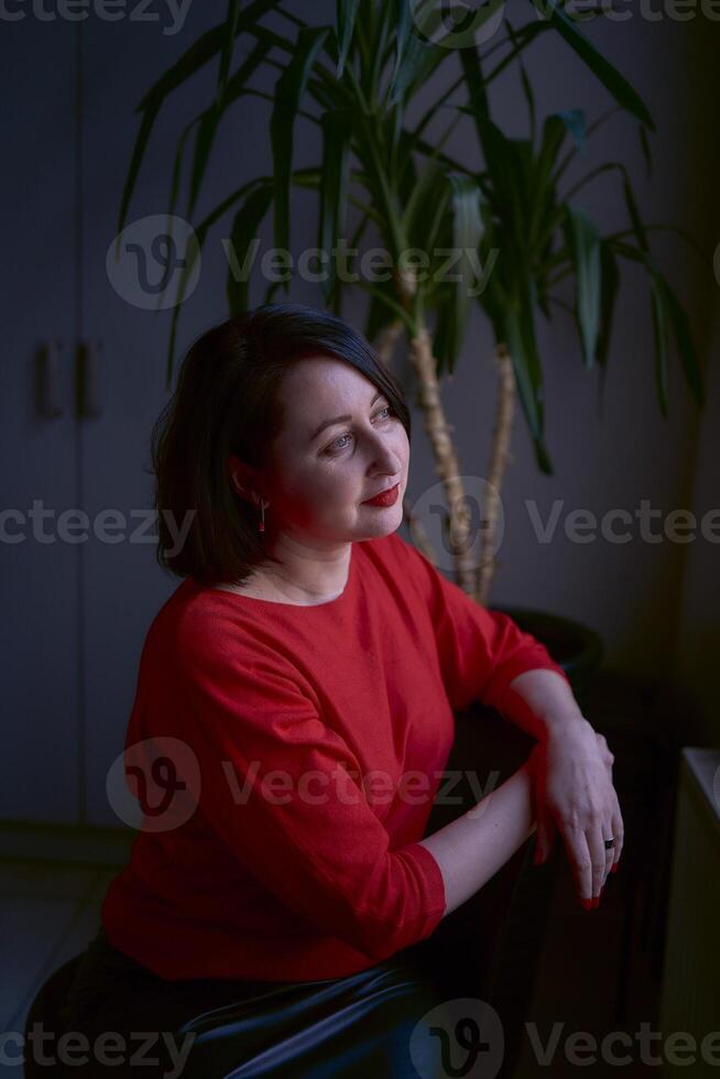 portrait of a brunette with a bob haircut in a red sweater and a leather mini skirt in the office photo