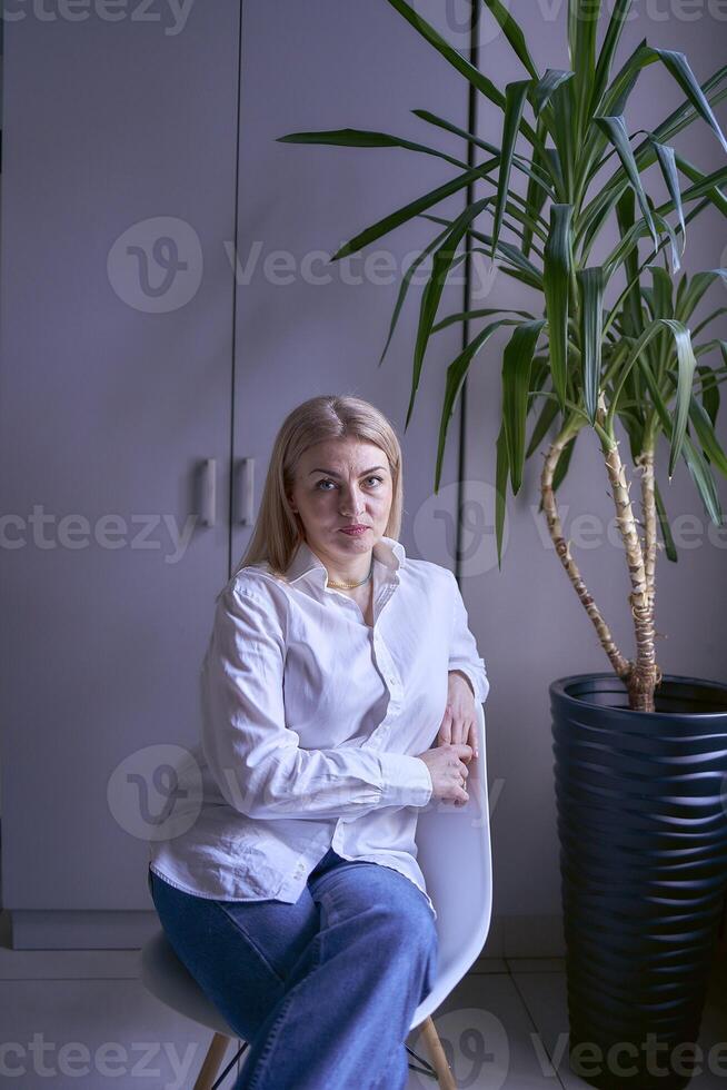 retrato de un rubia mujer en pantalones y un blanco camisa en el oficina foto