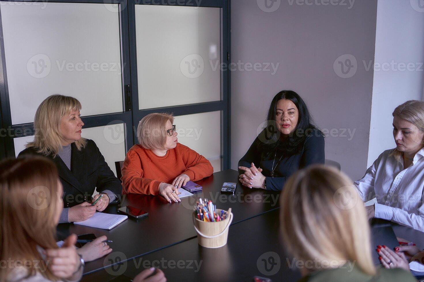 women in meeting in office, glass partitions behind them photo