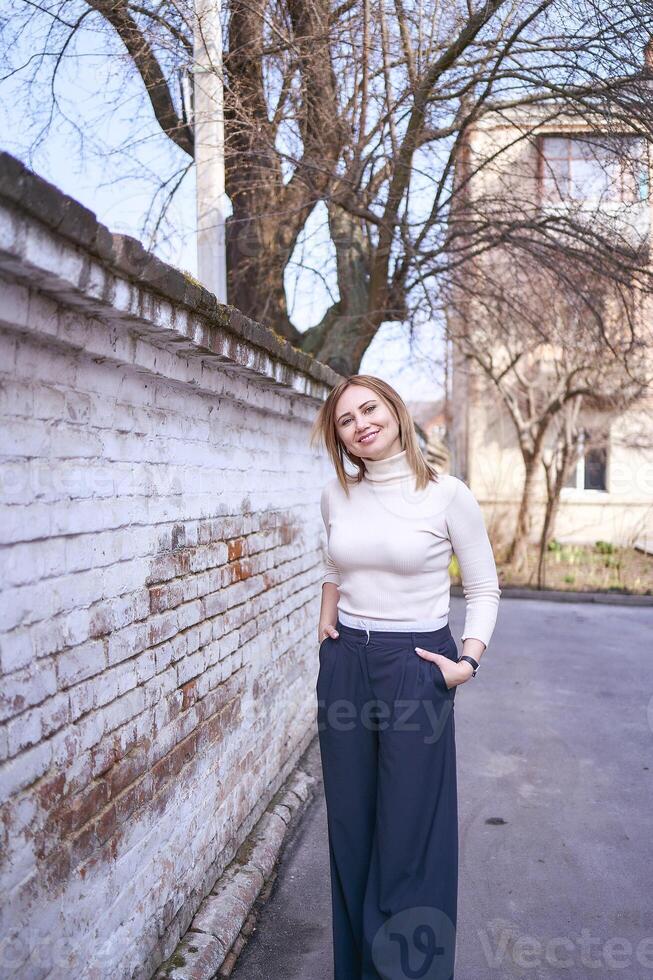 un hermosa medio años mujer en un suéter y elegante amplio pierna pantalones fuera de en un primavera día foto