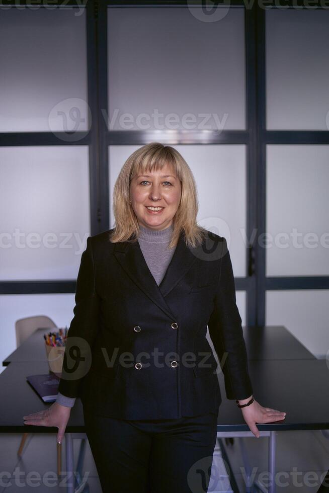 portrait of a blonde middle age woman in a business suit in the office photo