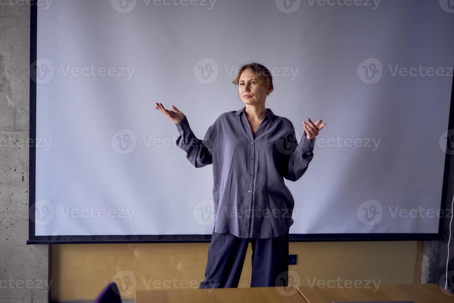 hermosa negocio mujer Hablando a un reunión en frente de un grande proyector pantalla foto