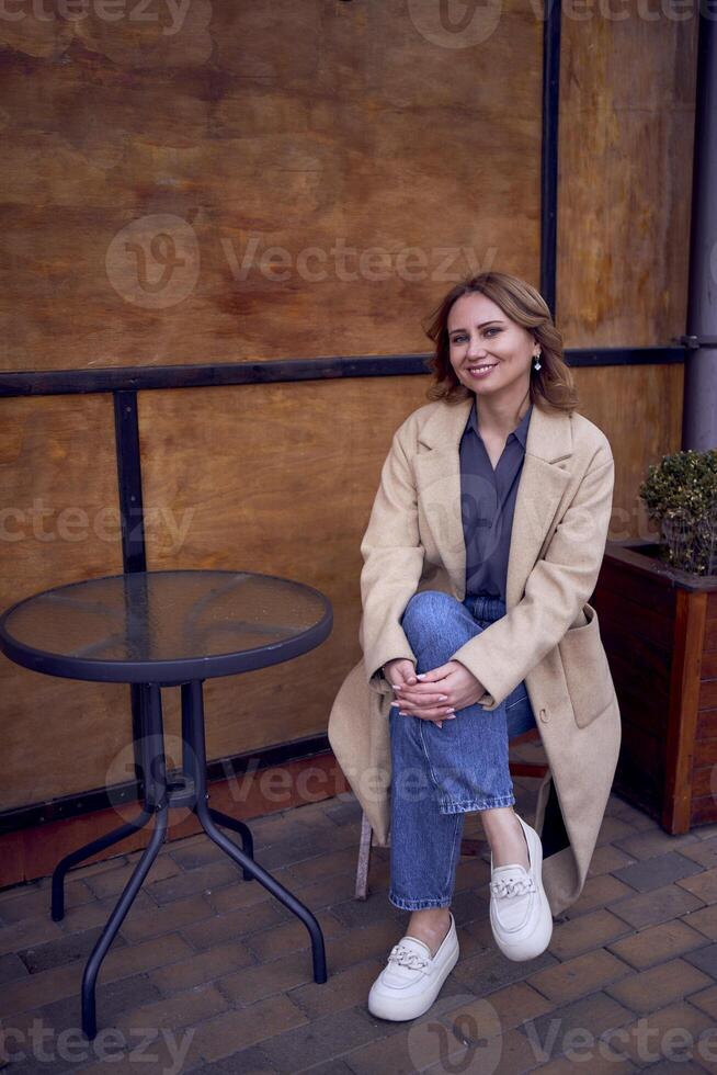 joven adulto mujer en pantalones y arena Saco con grunge fondo, oxidado pared con café letras foto