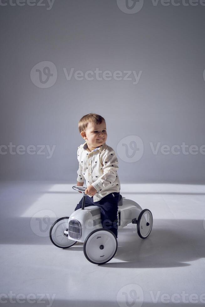 A toddler is enthusiastically playing with his toy car on his birthday photo