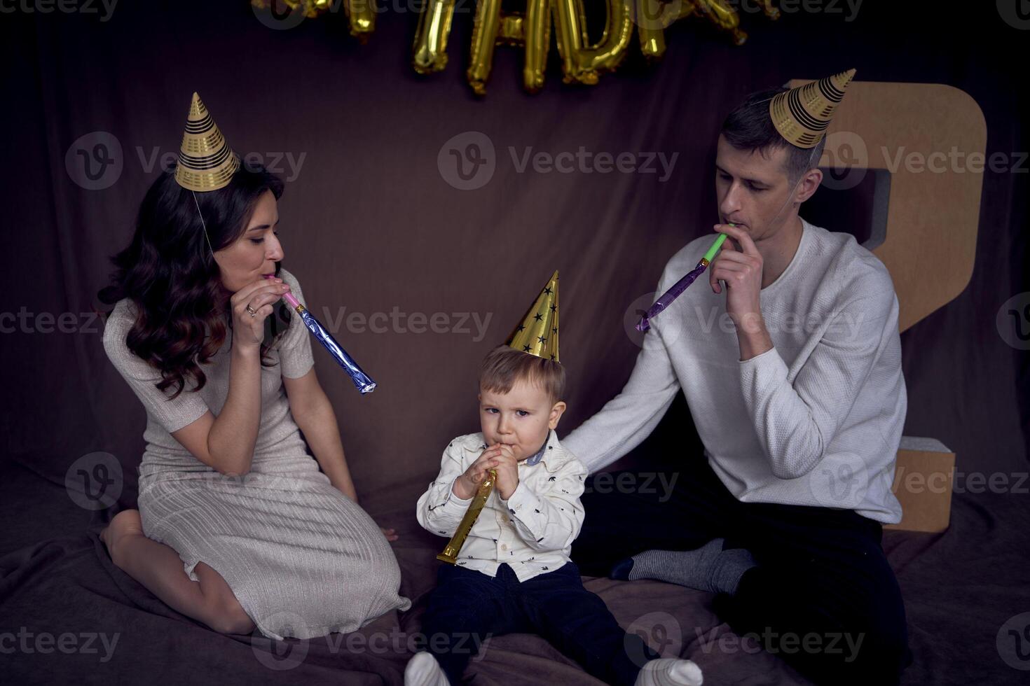 familia celebrando del niño cumpleaños vistiendo fiesta sombreros soplo tubería foto