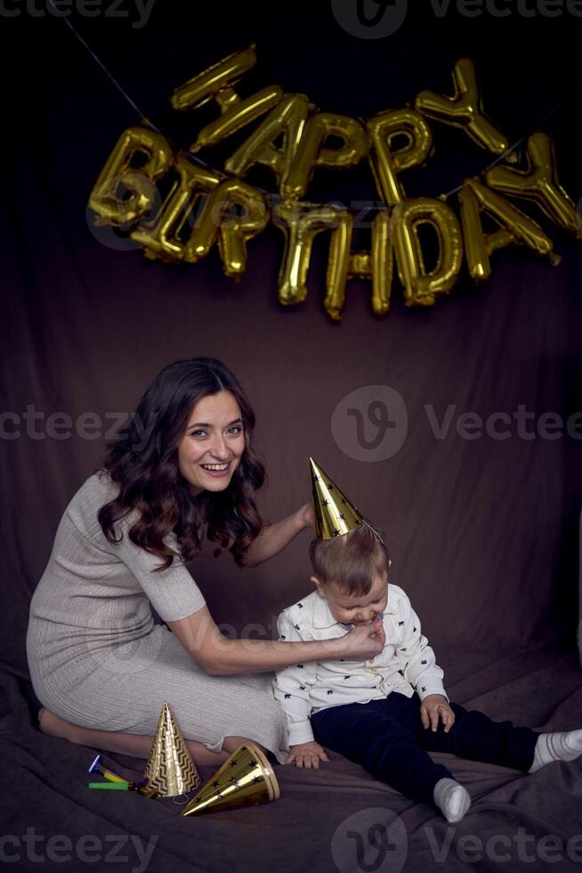 emocional mamá vendaje su niñito en un oro fiesta sombrero foto