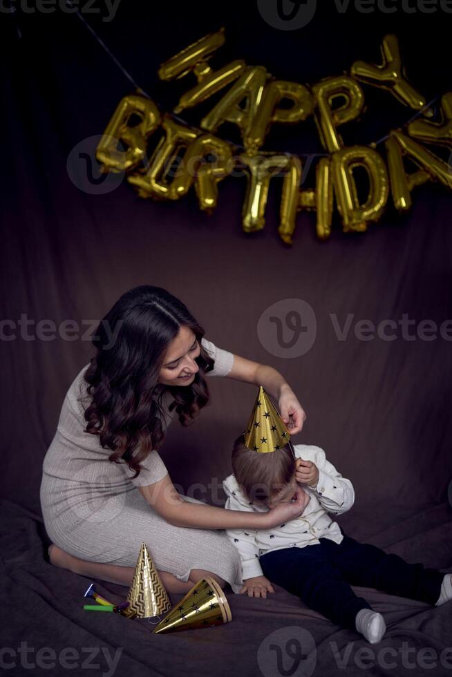 emocional mamá vendaje su niñito en un oro fiesta sombrero foto