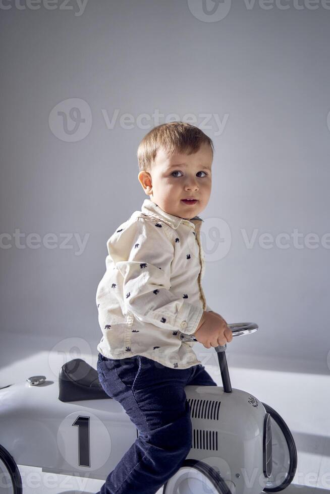 A toddler is enthusiastically playing with his toy car on his birthday photo