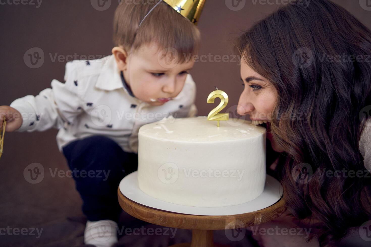very emotional mom and her little birthday boy eating cake photo
