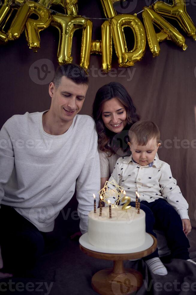 emocional padres reloj como su hijo golpes fuera el velas en el cumpleaños pastel foto