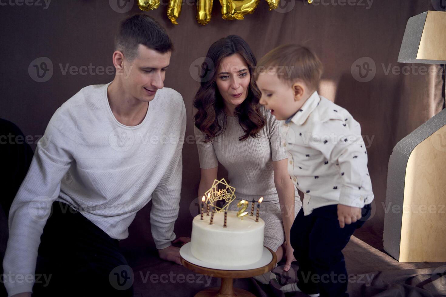 emotional parents watch as their son blows out the candles on the birthday cake photo