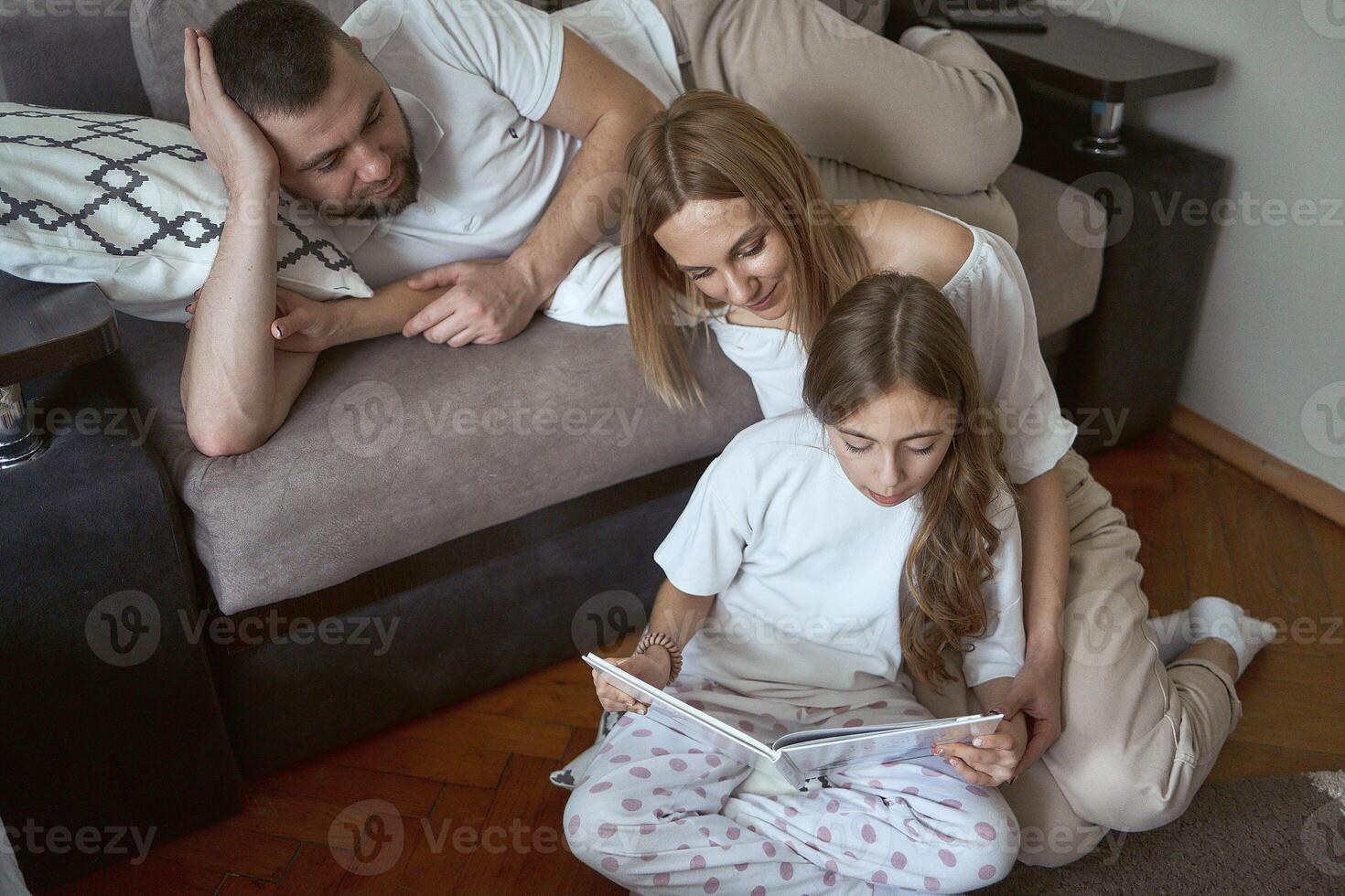 padres leer un libro con hija foto