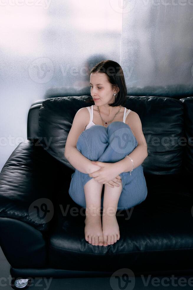 joven Adolescente niña luchando cerebro cáncer a foto disparar en estudio, metal muro, reflexión, negro sofá