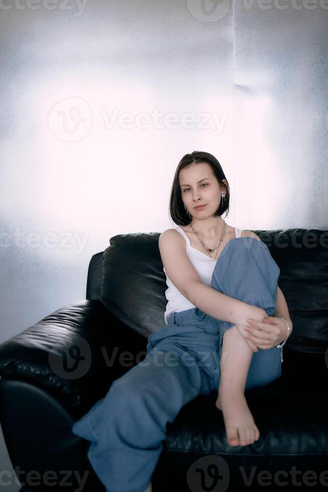 young teenage girl fighting brain cancer at photo shoot in studio, metal wall, reflection, black sofa