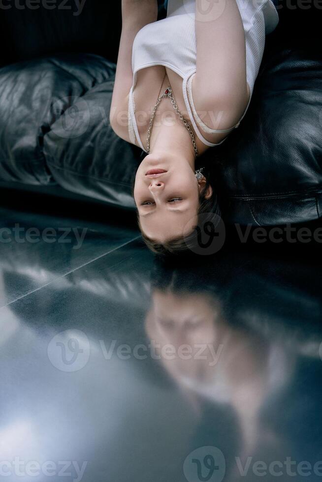 young teenage girl fighting brain cancer at photo shoot in studio, metal wall, reflection, black sofa