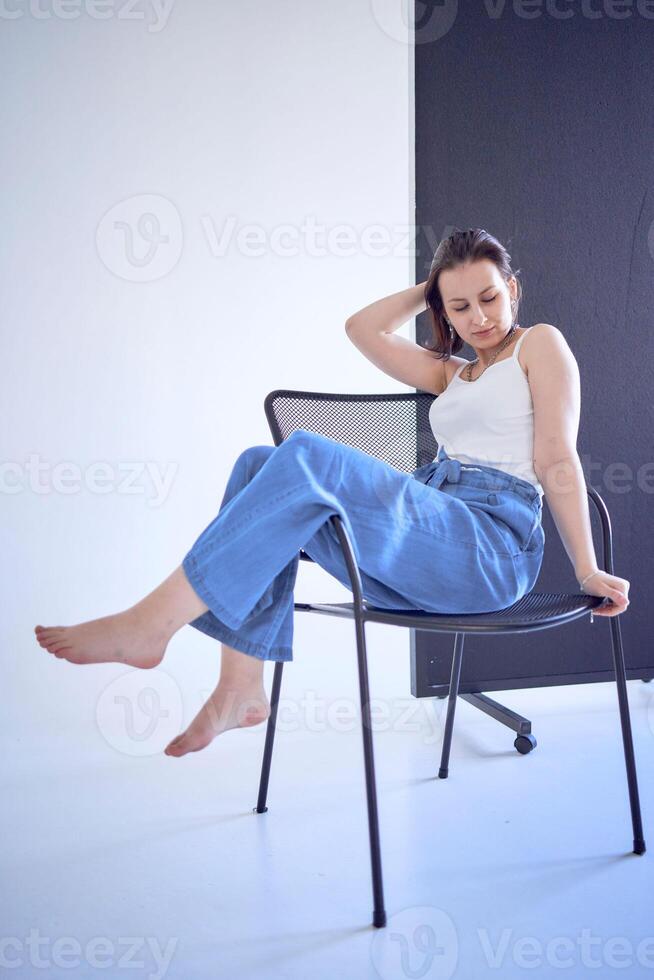 young teenage girl fighting brain cancer sitting on black chair on white background in studio photo