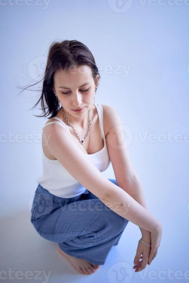 young teenage girl sits on a white cyclorama in the studio photo