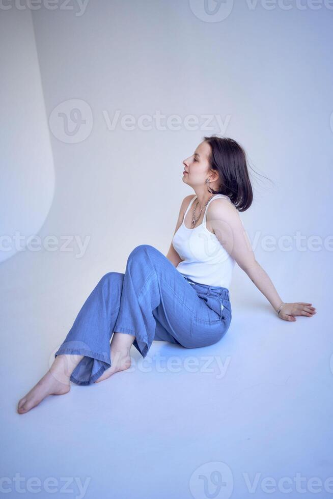 young teenage girl sits on a white cyclorama in the studio photo