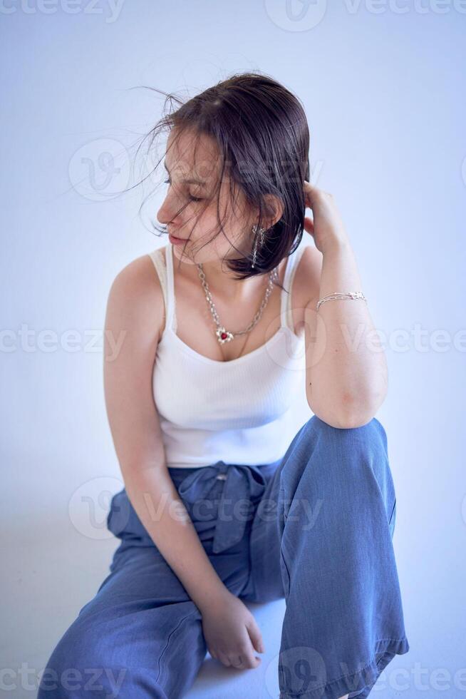 joven Adolescente niña se sienta en un blanco ciclorama en el estudio foto