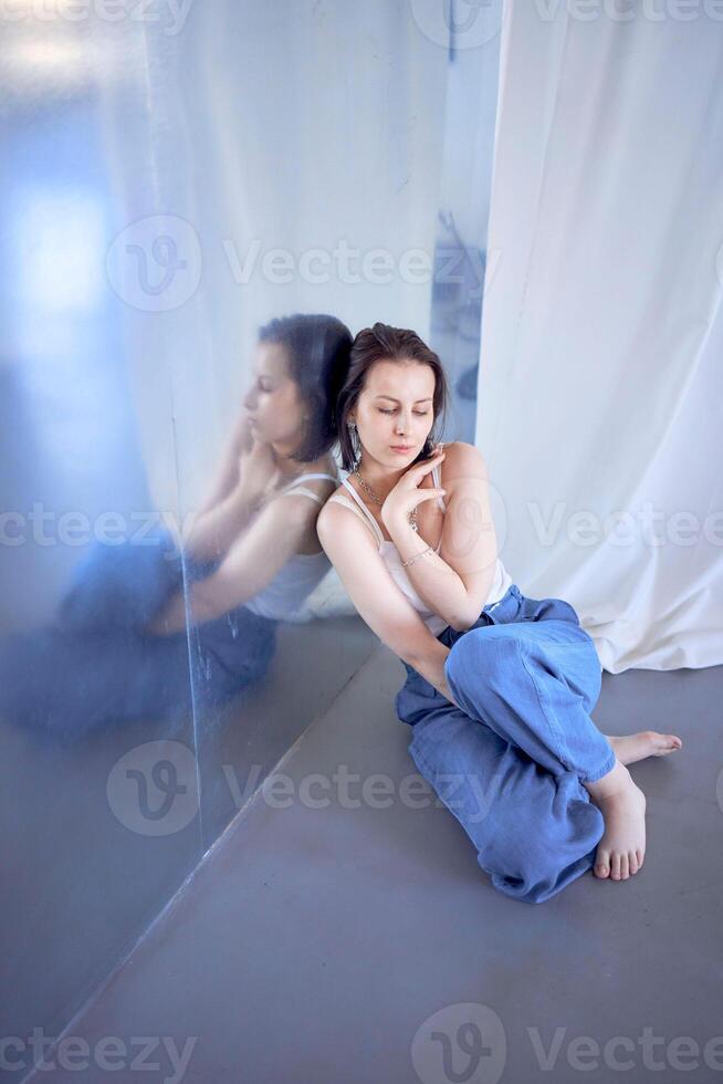 joven Adolescente niña luchando cerebro cáncer a foto disparar en estudio sentado en piso, propensión en contra metal muro, reflexión