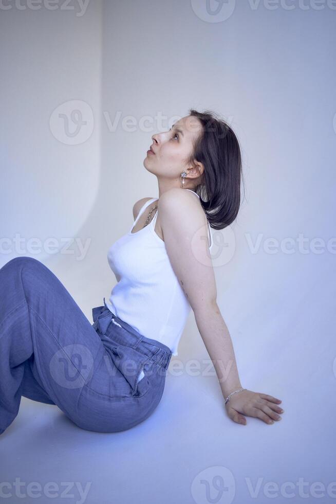 young teenage girl sits on a white cyclorama in the studio photo