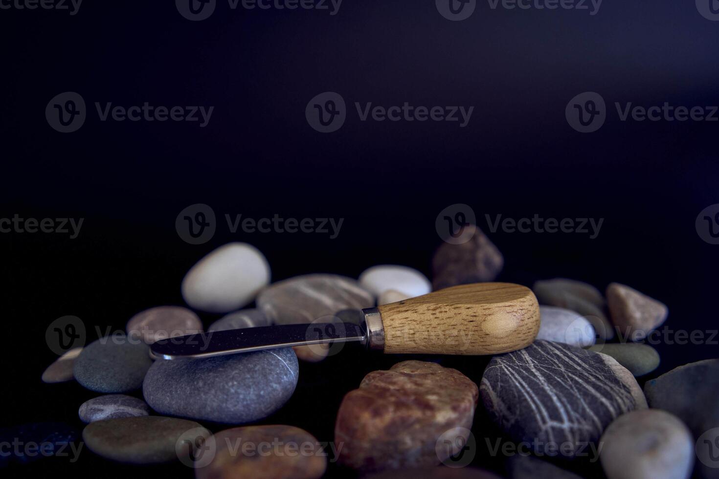 fish and cheese knife with a wooden handle on a black background with sea pebbles photo