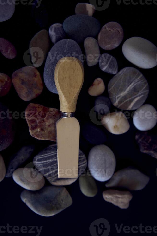 fish and cheese knife with a wooden handle on a black background with sea pebbles photo