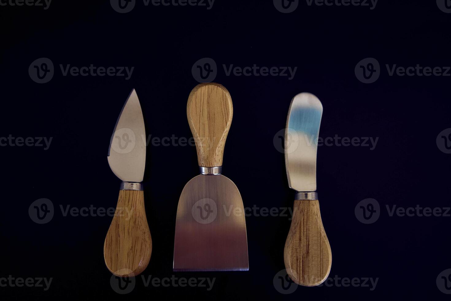 a set of fish and cheese knives with a wooden handle on a black background photo