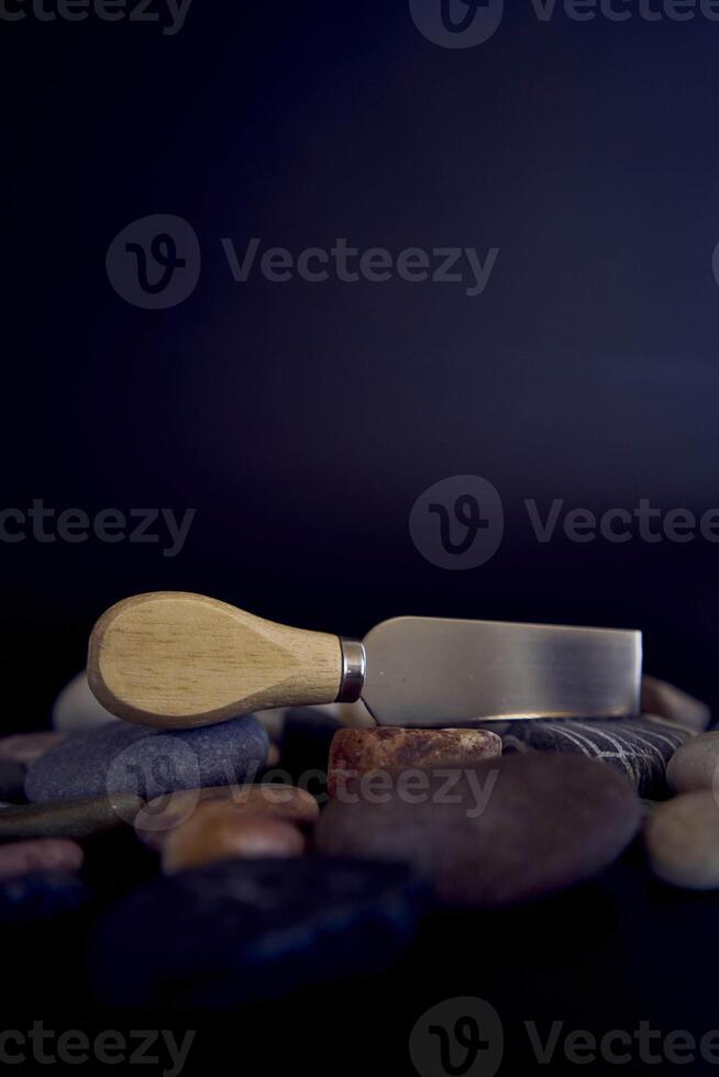 fish and cheese knife with a wooden handle on a black background with sea pebbles photo