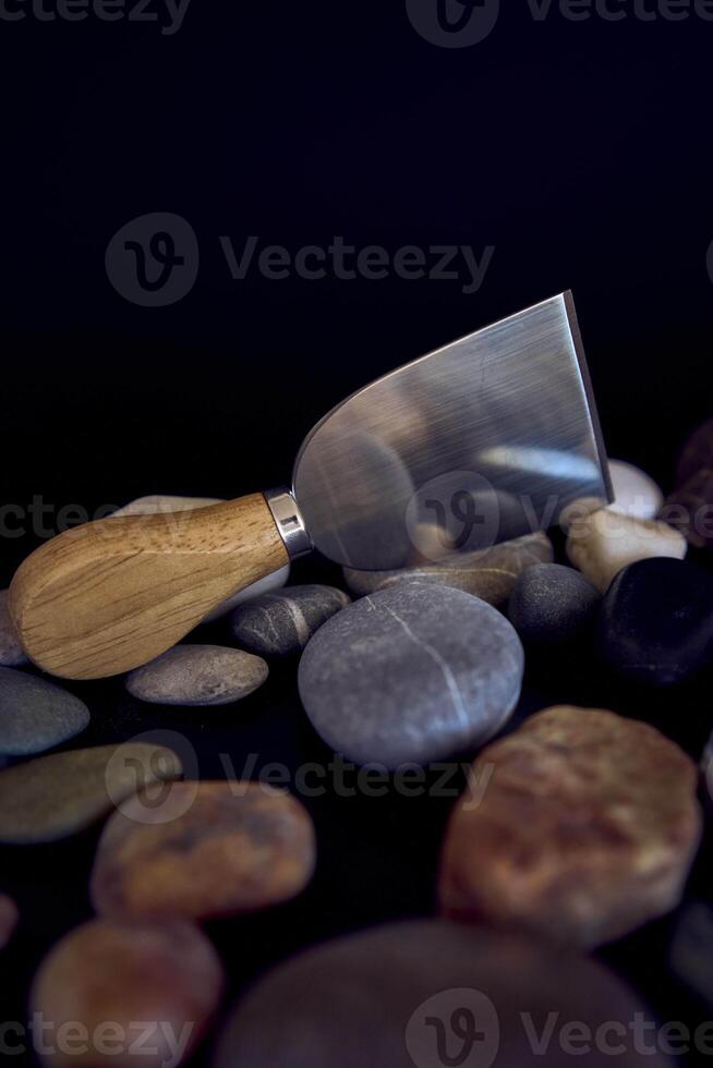 fish and cheese knife with a wooden handle on a black background with sea pebbles photo