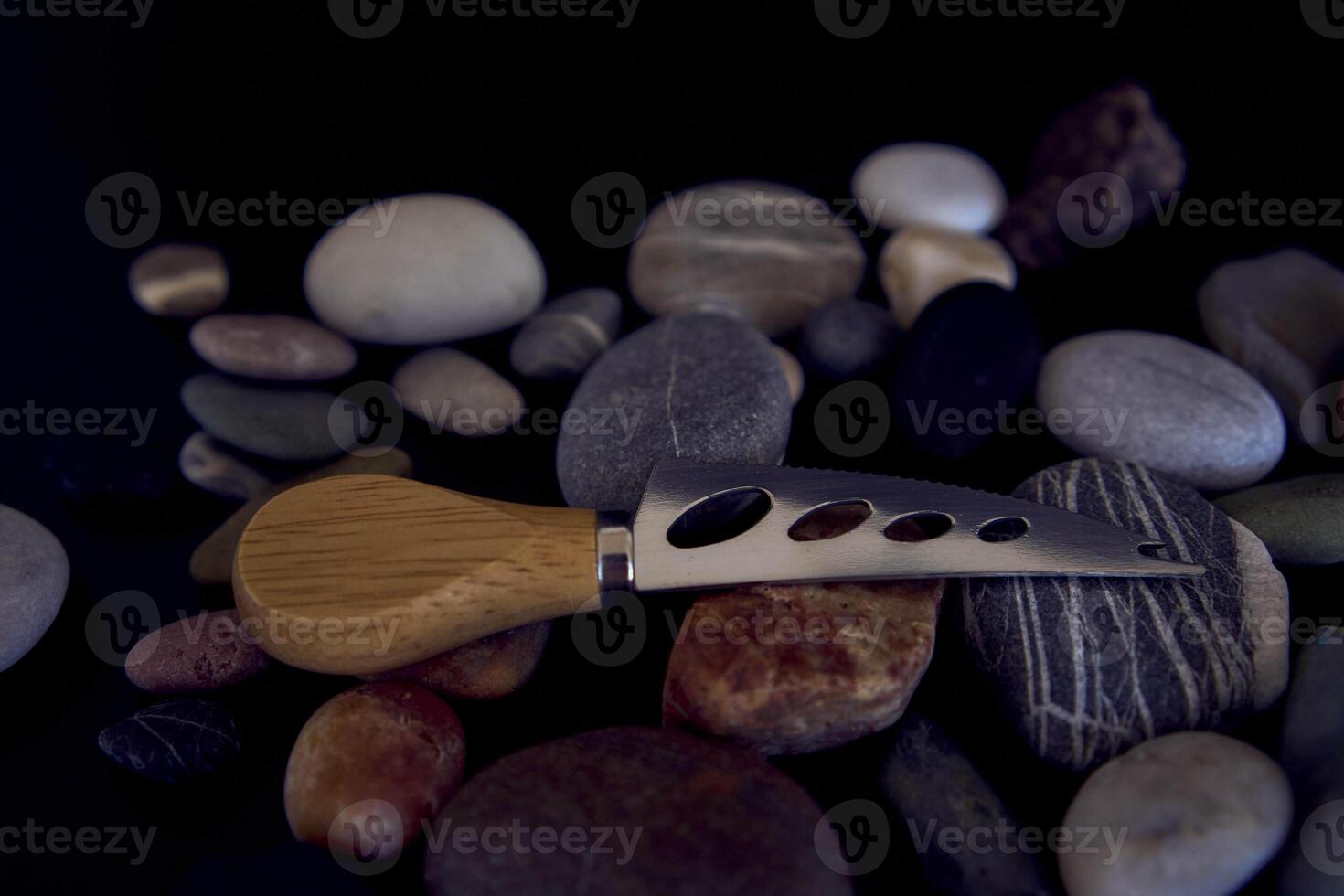 fish and cheese knife with a wooden handle on a black background with sea pebbles photo