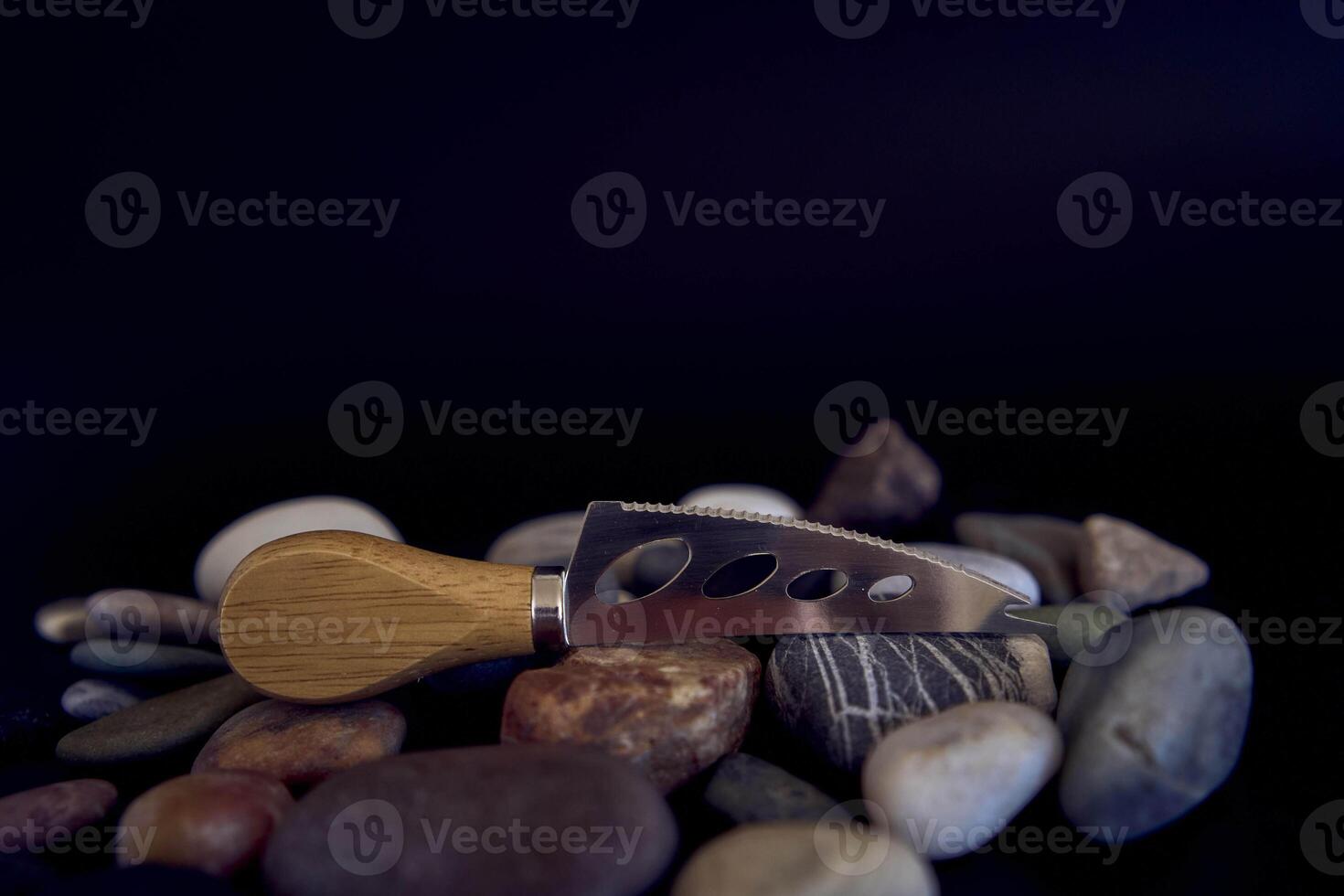 fish and cheese knife with a wooden handle on a black background with sea pebbles photo