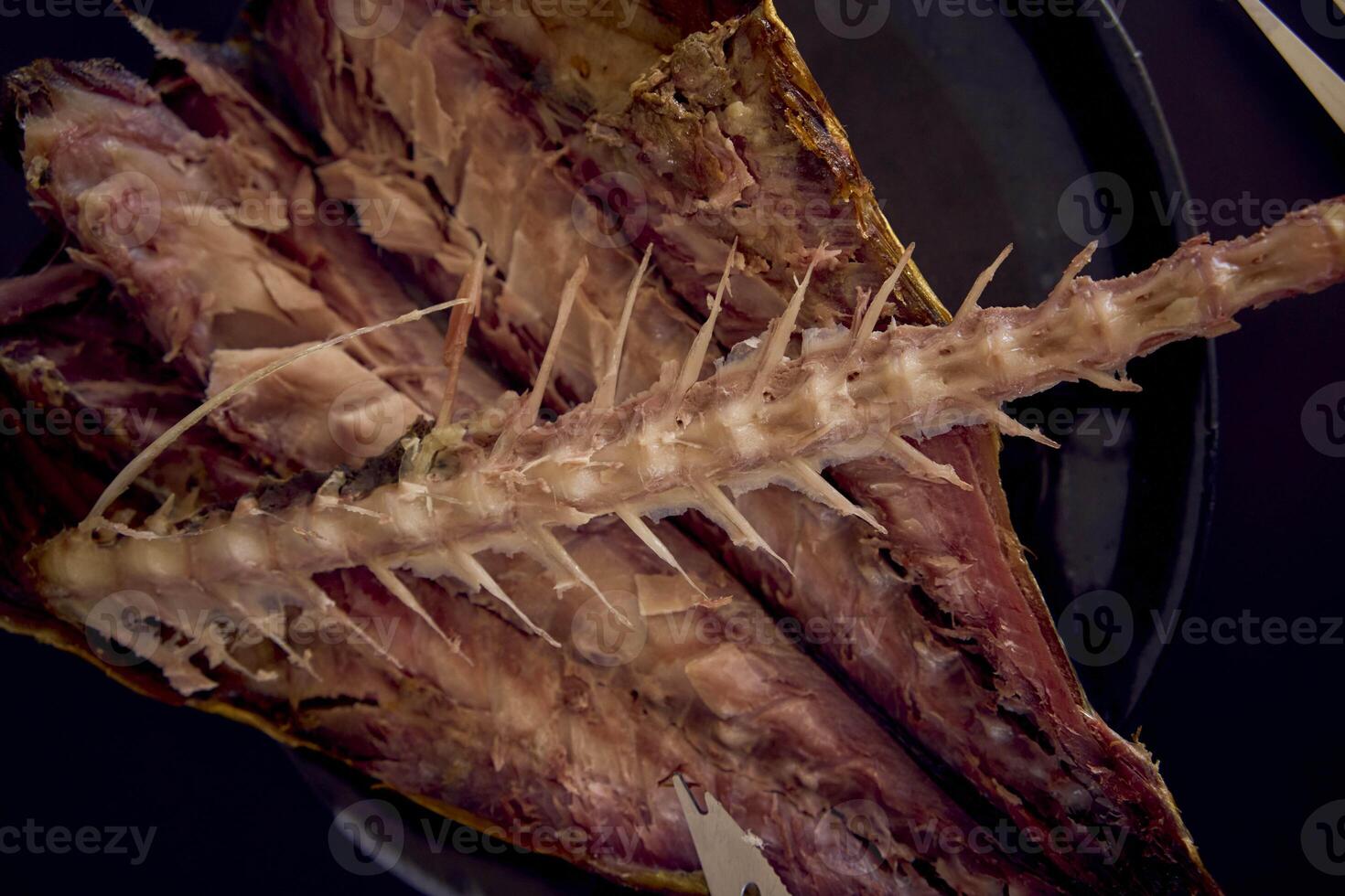 the  process of dissecting hot smoked golden horse mackerel with small knives photo