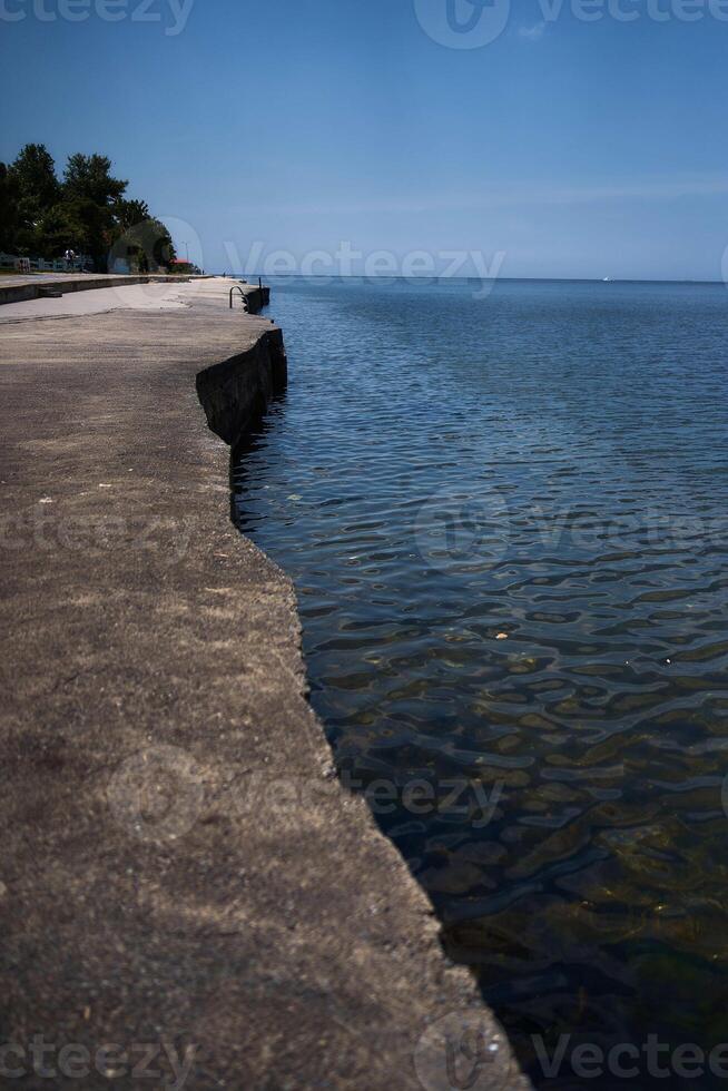 un hormigón terraplén y transparente mar agua foto