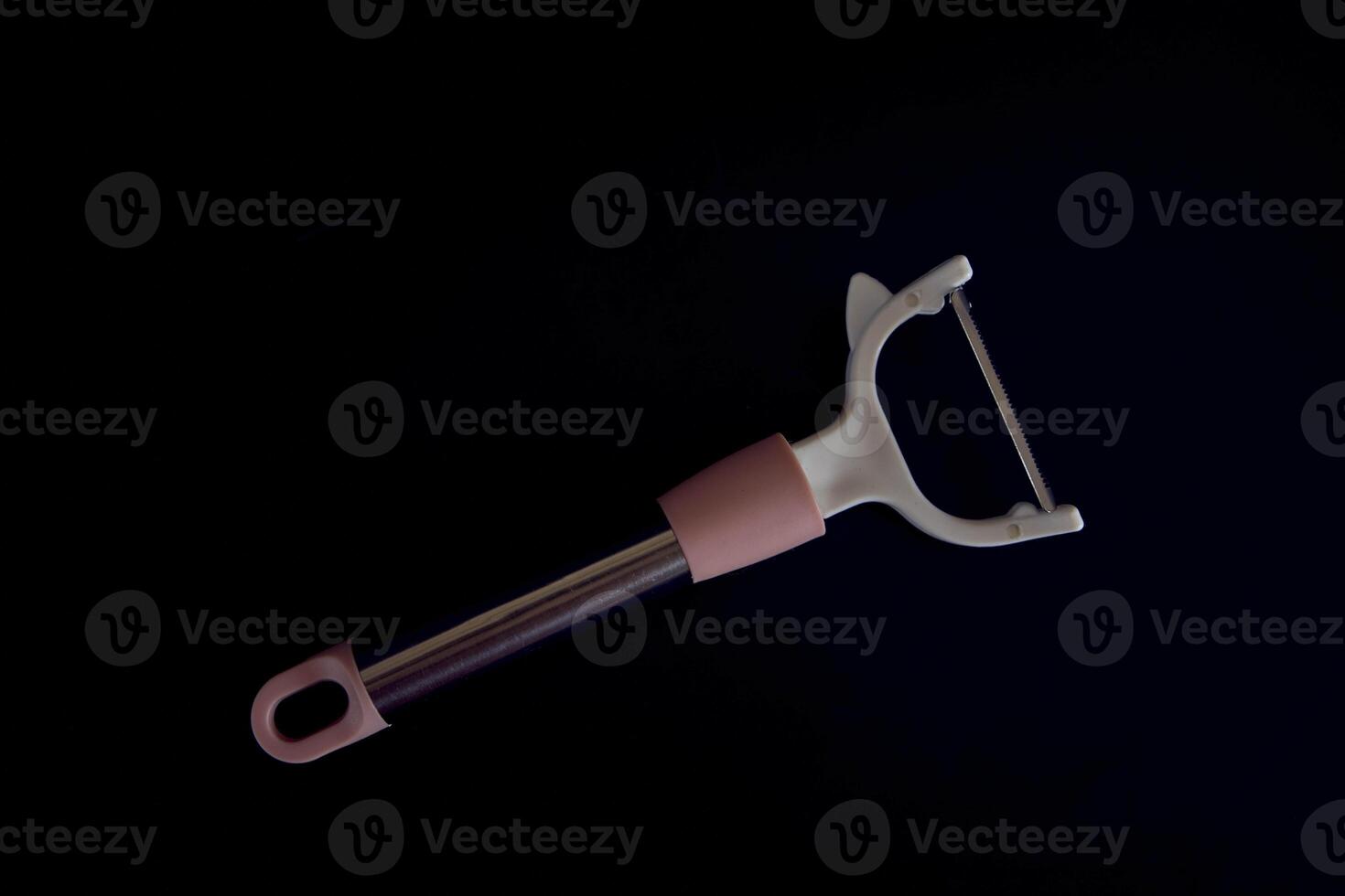 pink vegetable peeler on a black background photo