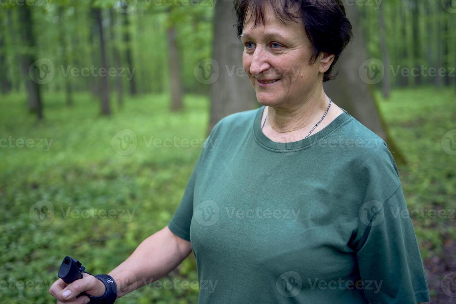 elderly woman is engaged in Nordic walking with sticks in the spring forest photo