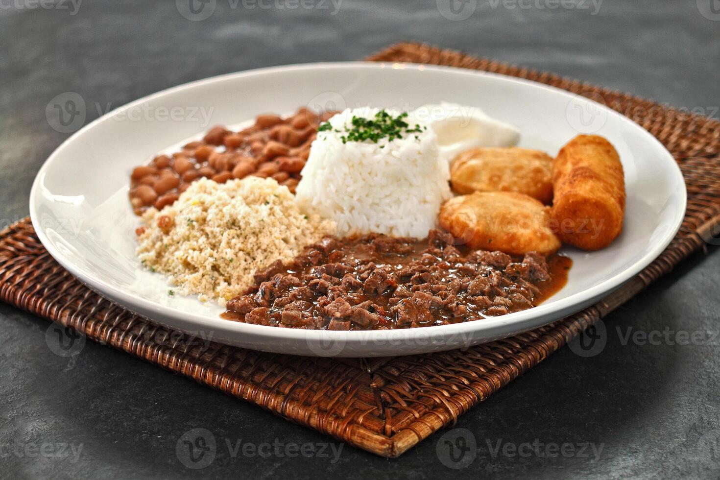 Beef mince with rice, beans, fried egg, pastry, farofa and breaded banana photo