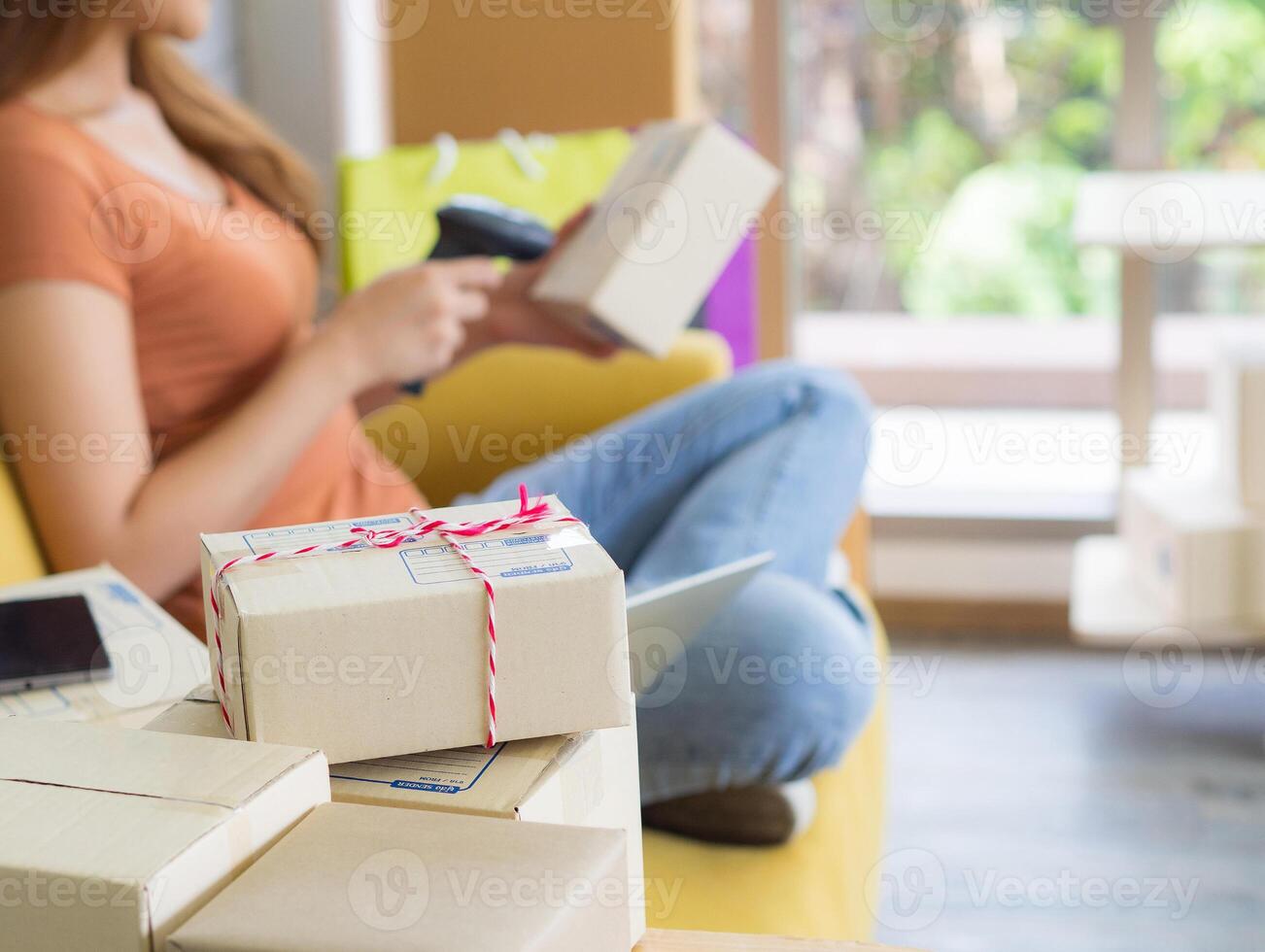 A businesswoman is an e-commerce entrepreneur sitting on a chair with the right hand holding the barcode reader and the left hand holding the parcel box. Business concept. E-commerce concept photo