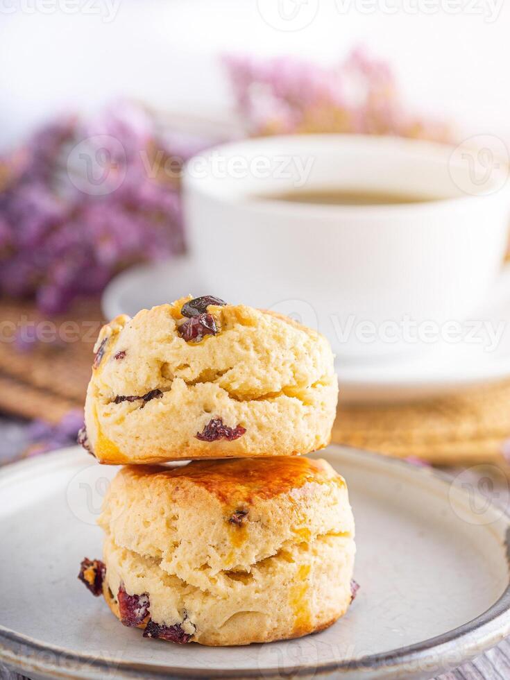Close-up of traditional British scones on a plate with a white coffee cup and flower blurred background. Space for text photo