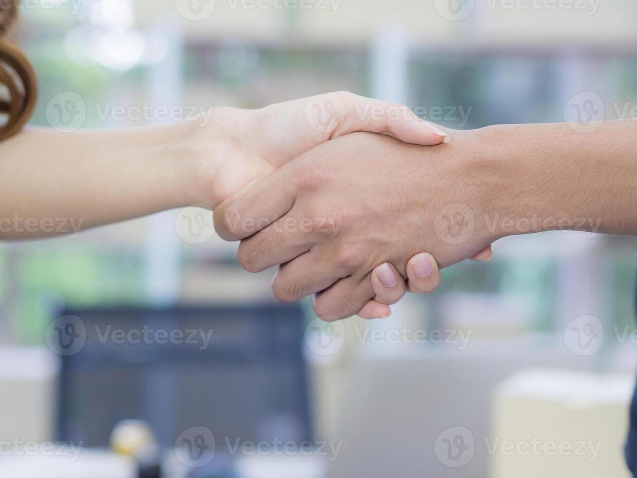 Business handshake after contract meeting in office. Young Woman and man shaking hands after meeting or negotiation to join partner business. Success joins partnership working with teamwork photo