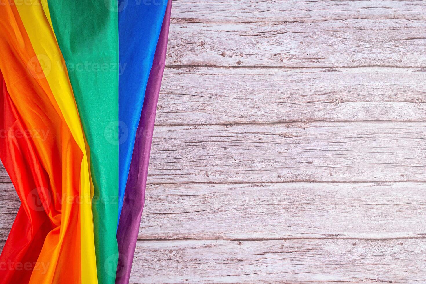 Close-up of LGBT flag on wooden table. Space for text photo