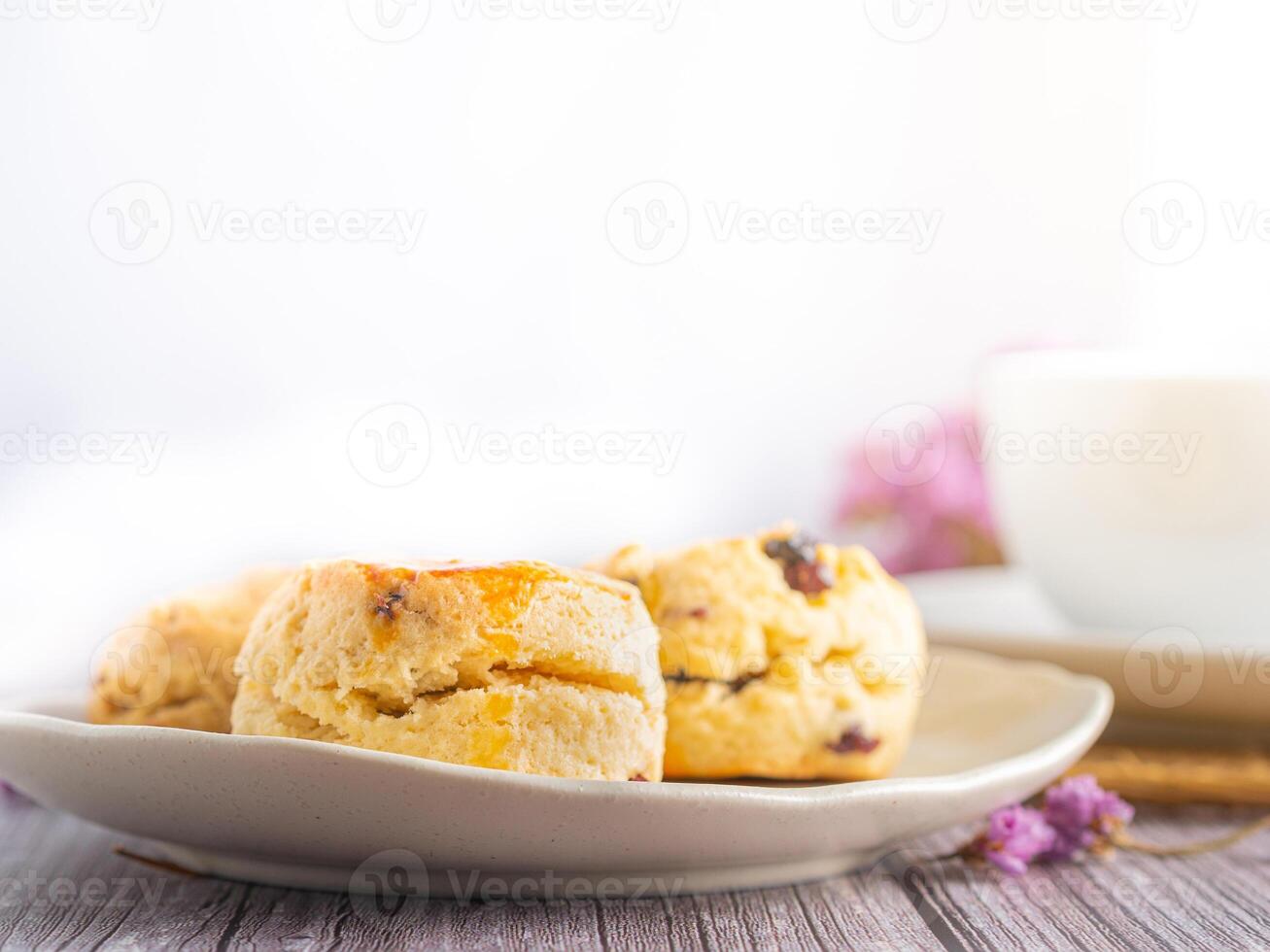 Close-up of traditional British scones on a plate and a tea hot cup with blurred background. Space for text photo
