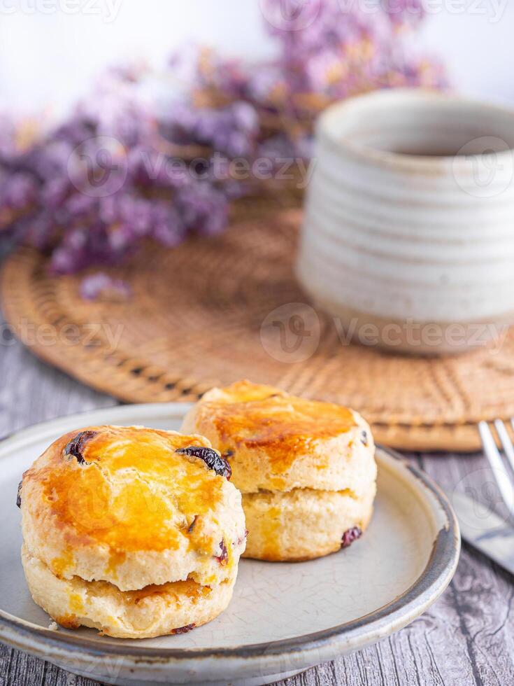 Close-up of traditional British scones on a plate with a cup of tea and flower blurred background. Space for text photo